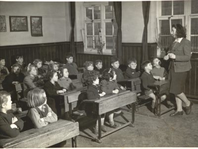 Children sitting in a classroom being taught by a teacher