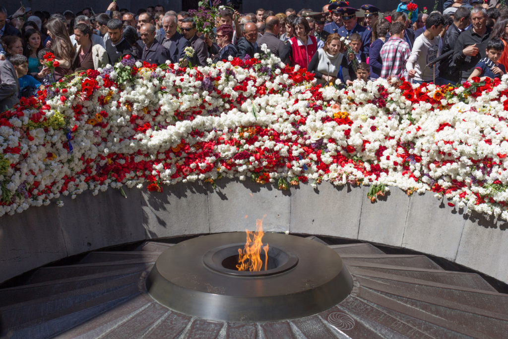 Flowers and people surround a memorial flame in Armenia