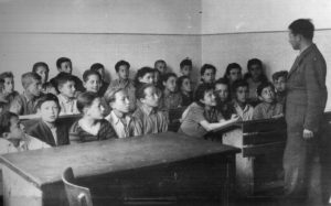 Children with a teacher in a classroom in a displaced persons camp post-WWII